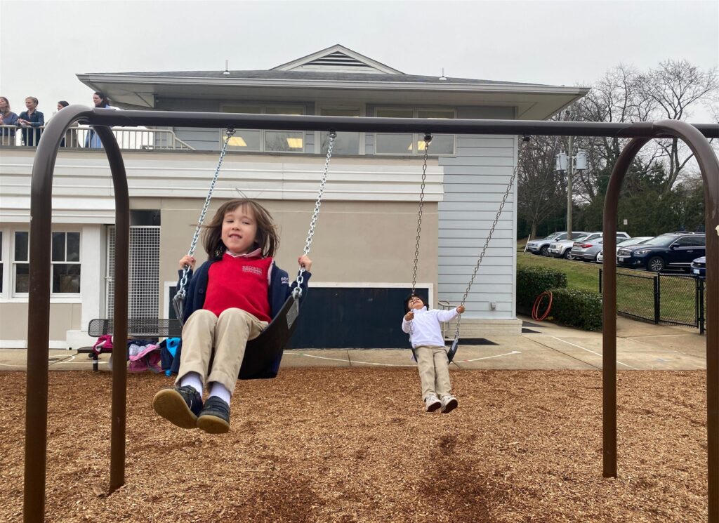 Two students swing on the swing set