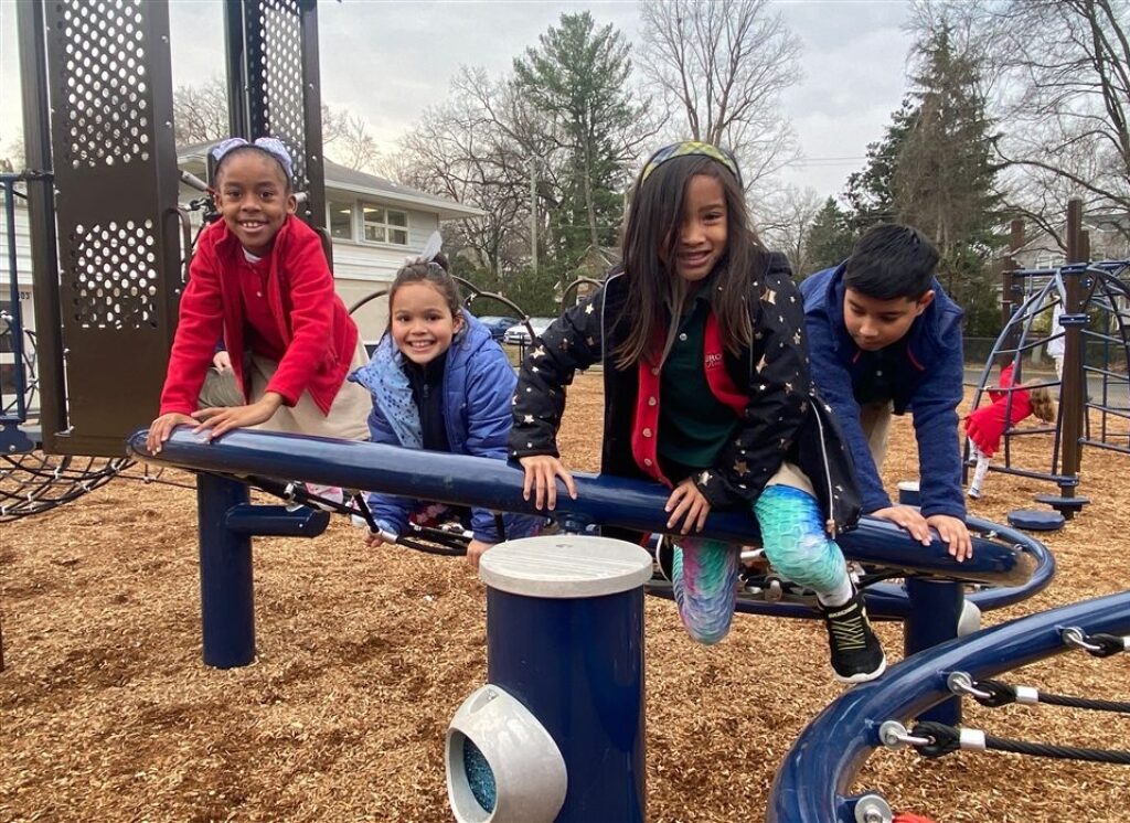 A group of children climb on playground equipment