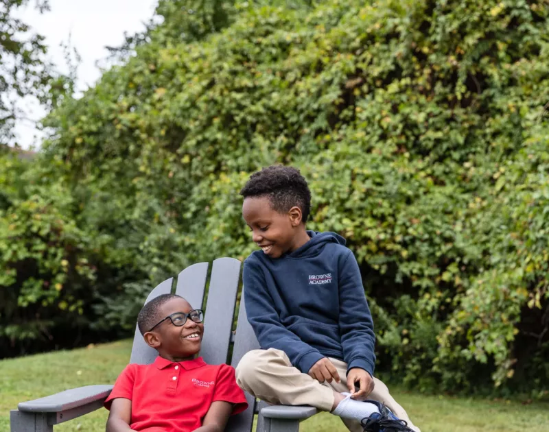 Two boys on chair on front lawn