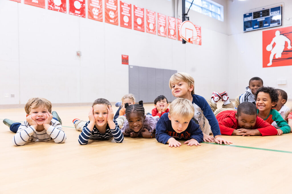 young children lying on gym floor smiling