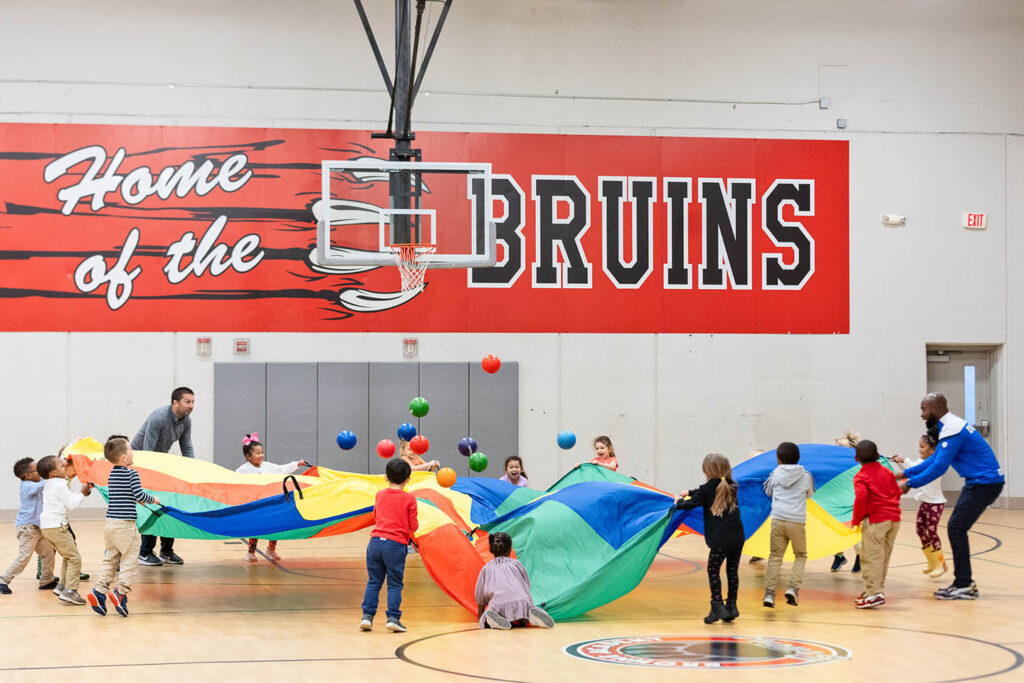 students and PE teachers play with the giant parachute